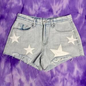 Blank NYC blue light wash denim shorts with white star patches.